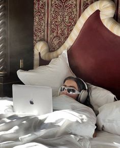 a man laying in bed with headphones on using a laptop