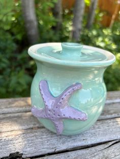 a ceramic container with a starfish design on the lid sitting on a wooden table