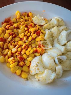 a white plate topped with boiled corn and sliced up egg shells next to seasoning