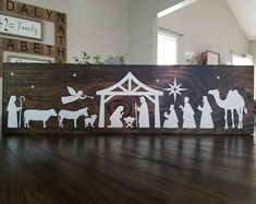 a wooden sign with the silhouettes of people and nativity scene on it sitting on a wood floor