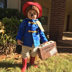 a young boy dressed as paddington bear holding a suitcase