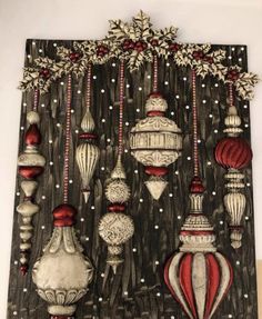 an art work with red and white ornaments hanging from the side of a black wall