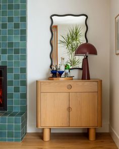 a wooden cabinet with a mirror above it and a fire place in the corner next to it