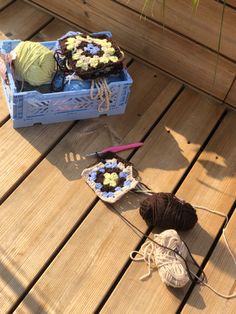 two crocheted balls of yarn sitting on a wooden floor next to a blue box