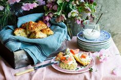 a table topped with lots of food next to purple and white flowered vases