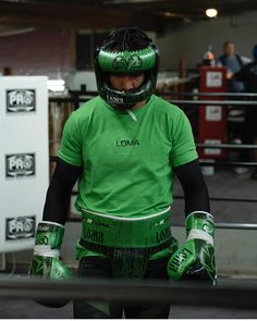 a man wearing green and black gear in a boxing ring with his hands on his hips