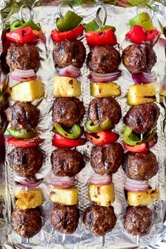 skewered meatballs and vegetables on a sheet of aluminum foil with peppers, onions, and pineapples