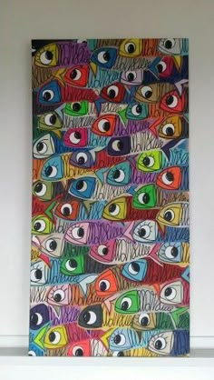 an art piece with many different colored fish on it's face and eyes painted on the wall