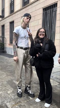 two people standing next to each other on a sidewalk