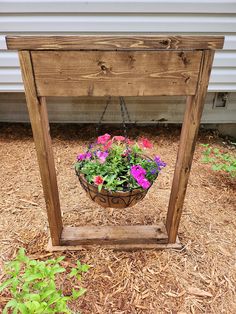 a potted plant sitting on top of a wooden stand next to a building with flowers in it