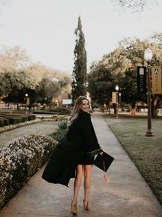 a woman is walking down the sidewalk wearing a black coat