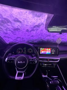 the interior of a car with purple lighting and dashboard controls, including an entertainment system