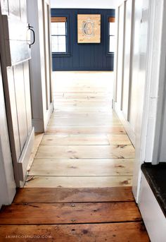 an empty hallway with wood flooring and blue painted wall in the background, along with a wooden sign that reads c