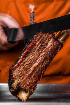 a person holding a knife over a piece of meat