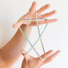 a person holding out their hand with string wrapped around it in the shape of a star