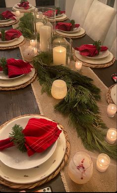 the table is set for christmas dinner with candles and napkins