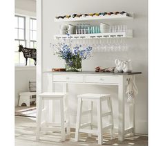 two white bar stools sitting in front of a counter with bottles and glasses on it