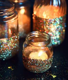 there are many jars that have candles inside of them on the table with confetti scattered around them