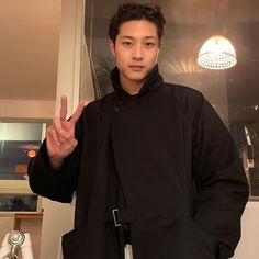 a young man standing in front of a mirror making the peace sign