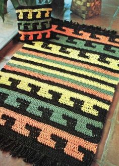 a crocheted rug is laying on the floor next to a potted plant