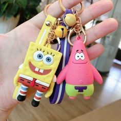 someone is holding two keychains in their hand, one has a spongebob figure on it