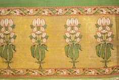 an embroidered cloth with flowers and leaves on the border, in green and gold colors