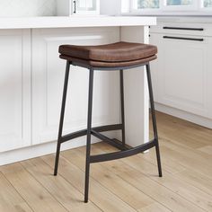 a brown leather seat on a black metal bar stool in a white kitchen with wood flooring