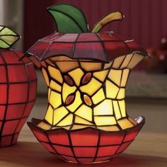 two stained glass apple lamps sitting on top of a wooden table next to each other