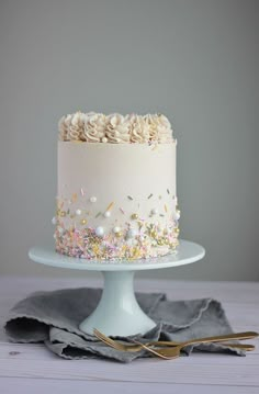 a white cake with sprinkles on it sitting on top of a table