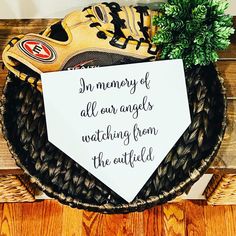 a baseball glove and ball mitt sitting on top of a wooden table next to a sign