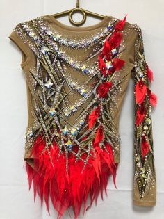 a woman's top with red feathers and sequins on the back, hanging from a hanger