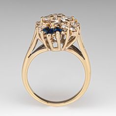 a yellow gold ring with blue and white stones in the center, on a gray background