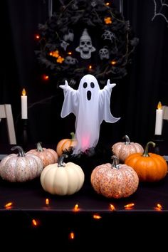 a table topped with lots of fake pumpkins and ghost decorations on top of it