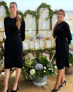 two beautiful women standing next to each other in front of a table with pictures on it