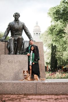 a man and woman standing next to a dog in front of a statue