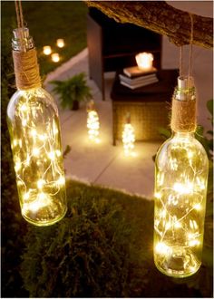 two glass bottles with lights hanging from them