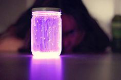 a woman sitting at a table in front of a jar with water droplets on it