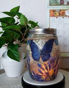 a glass jar sitting on top of a table next to a potted plant