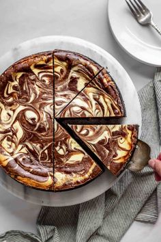 a chocolate cake on a plate with one slice cut out and someone holding a knife