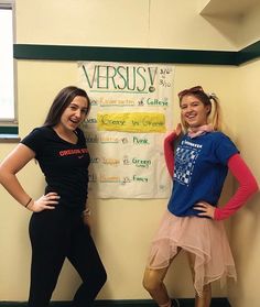 two girls standing next to each other in front of a wall with a sign on it