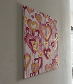 a painting hanging on the side of a wall with hearts painted all over it in pink, yellow and red