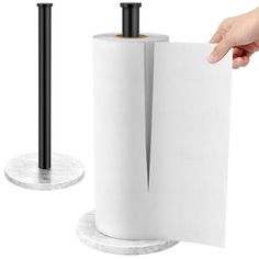 a person holding a roll of toilet paper in front of two black and white holders