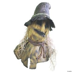 a scarecrow wearing a black hat and scarf with fringes on his head, standing against a white background