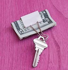 a bunch of money sitting on top of a pink table next to a keychain