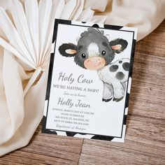 a card with a cow on it is sitting next to a white cloth and paper fan