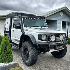 a white and black jeep parked in front of a house