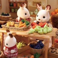 two rabbits sitting at a table with fruits and vegetables