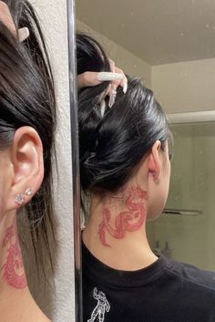 a woman with tattoos on her neck is looking at herself in the mirror