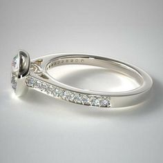 a white gold ring with diamonds on the side and an oval shaped diamond in the center