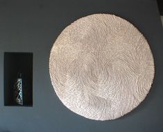 a white circular wall hanging on the side of a gray wall next to a black box